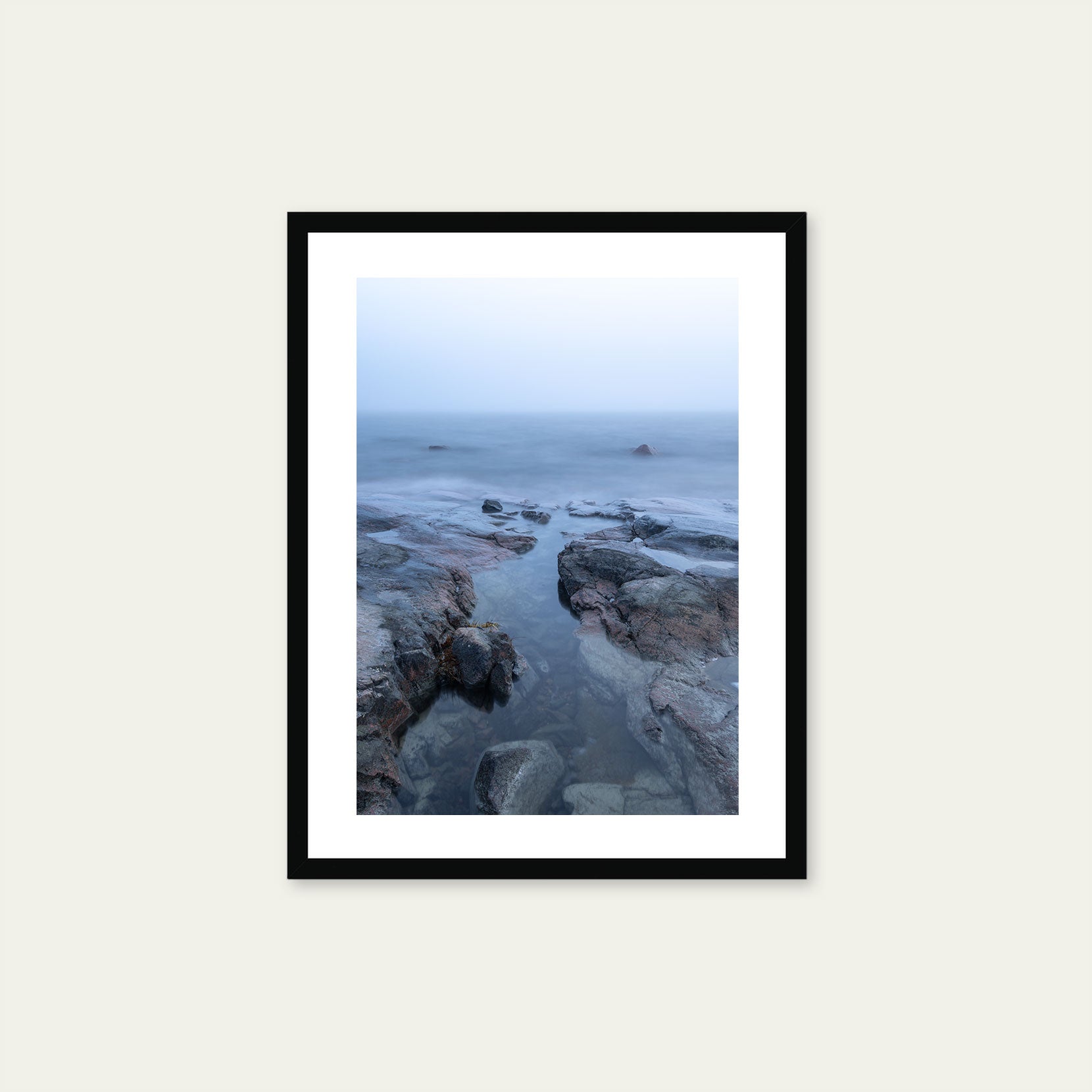 A black framed print of a rocky coastline in fog