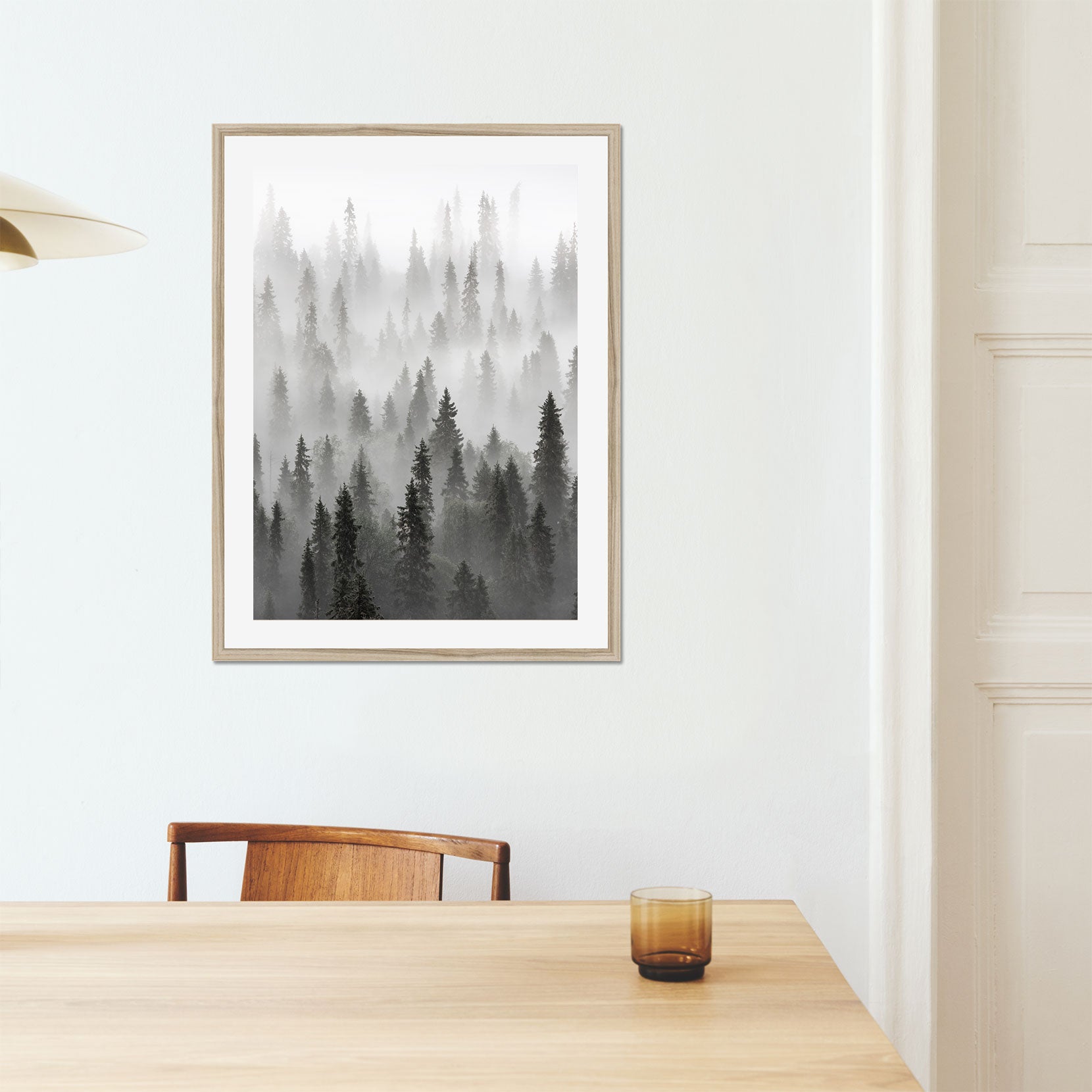 A framed print of a forest with lingering fog
