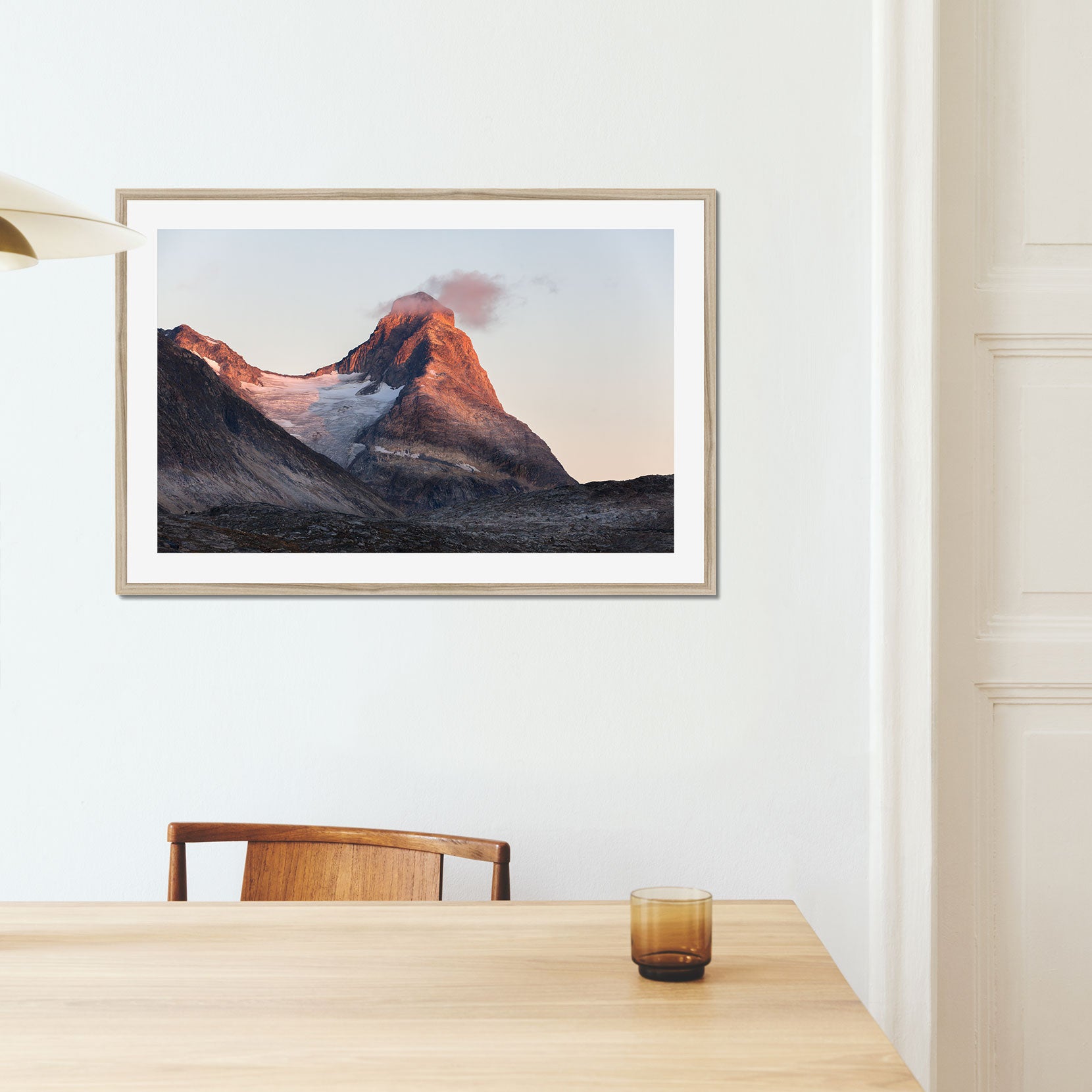 A framed print of a mountain peak at sunset