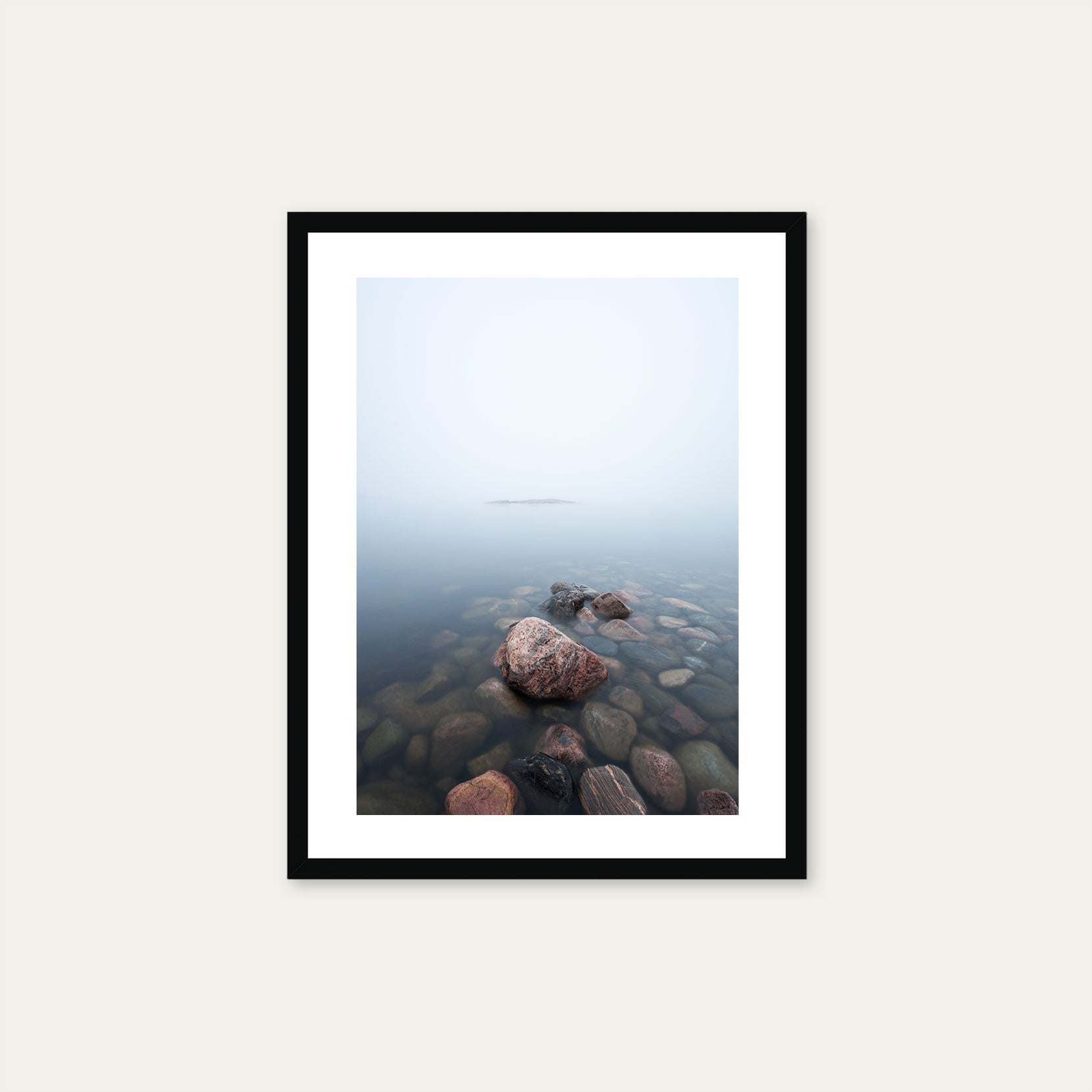 A black framed print of rocks in the sea on a foggy day