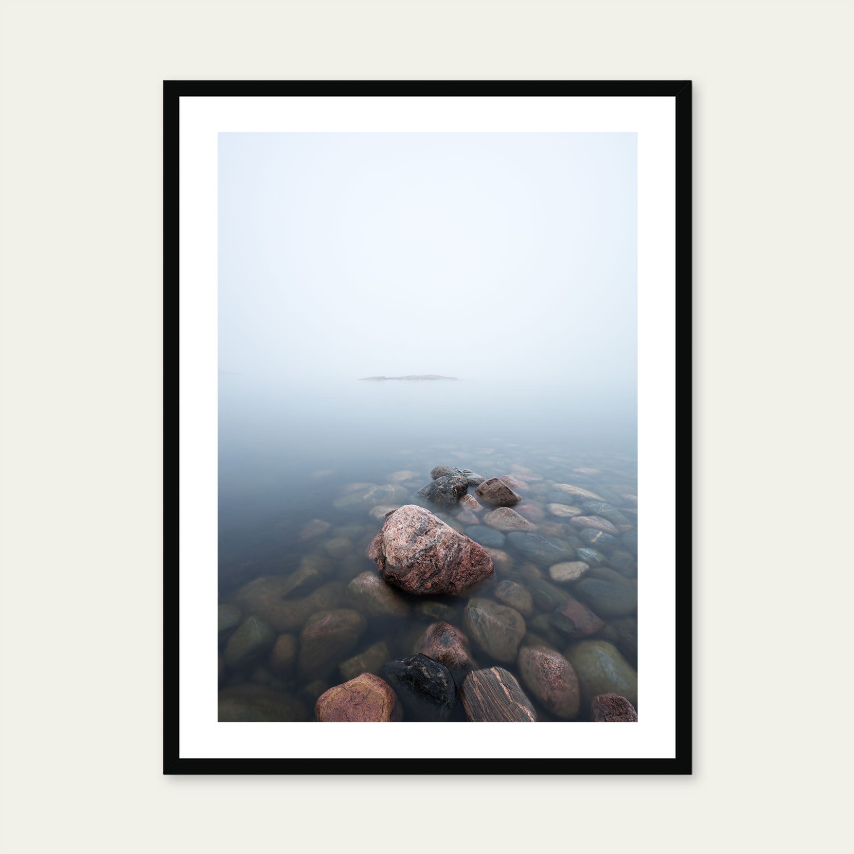 A black framed print of rocks in the sea on a foggy day