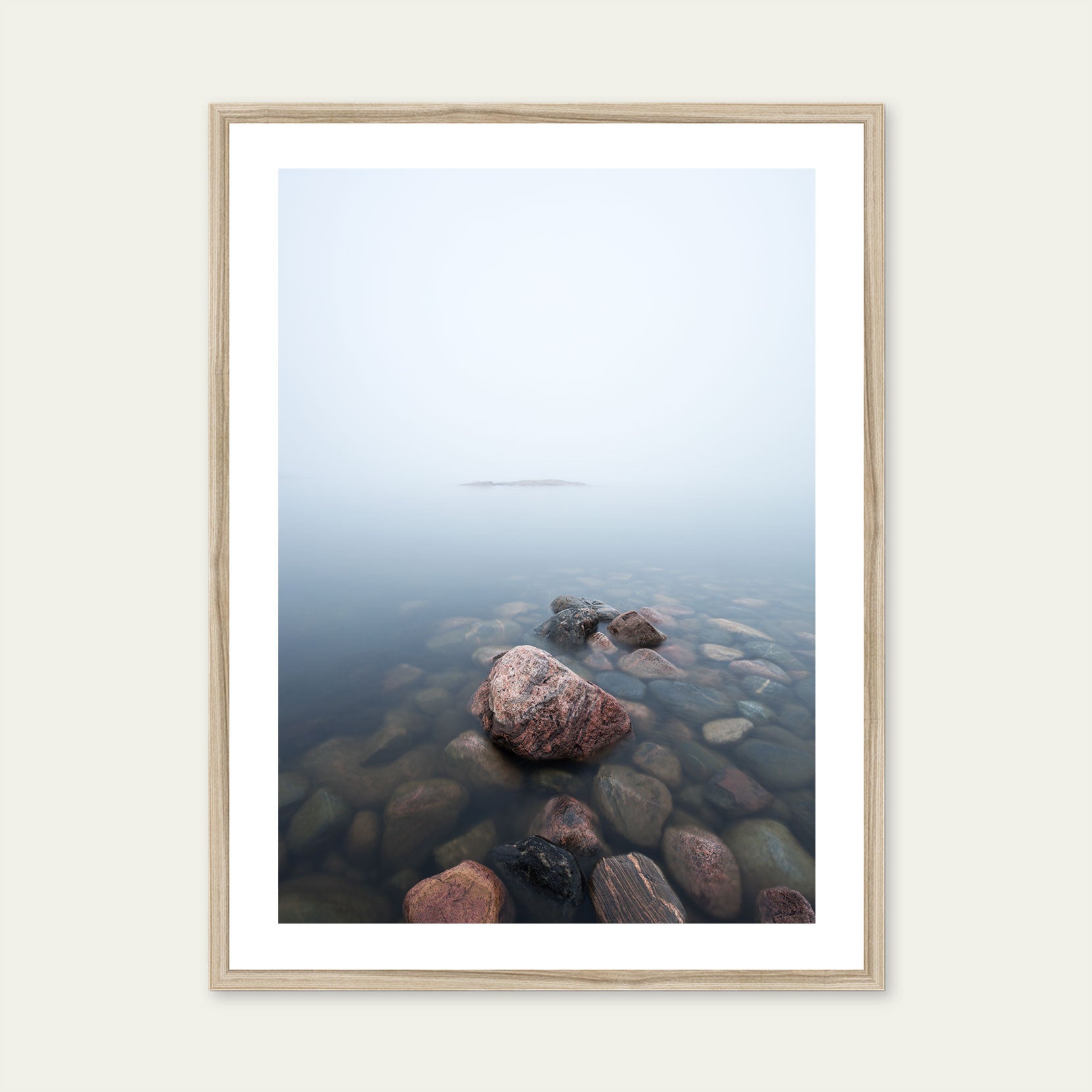 A wood framed print of rocks in the sea on a foggy day