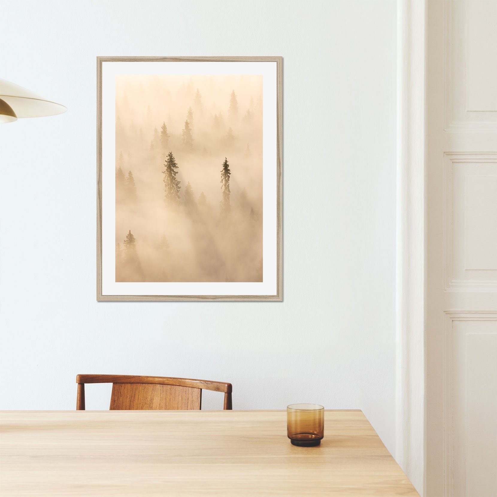A framed print of tall pine trees in a golden fog